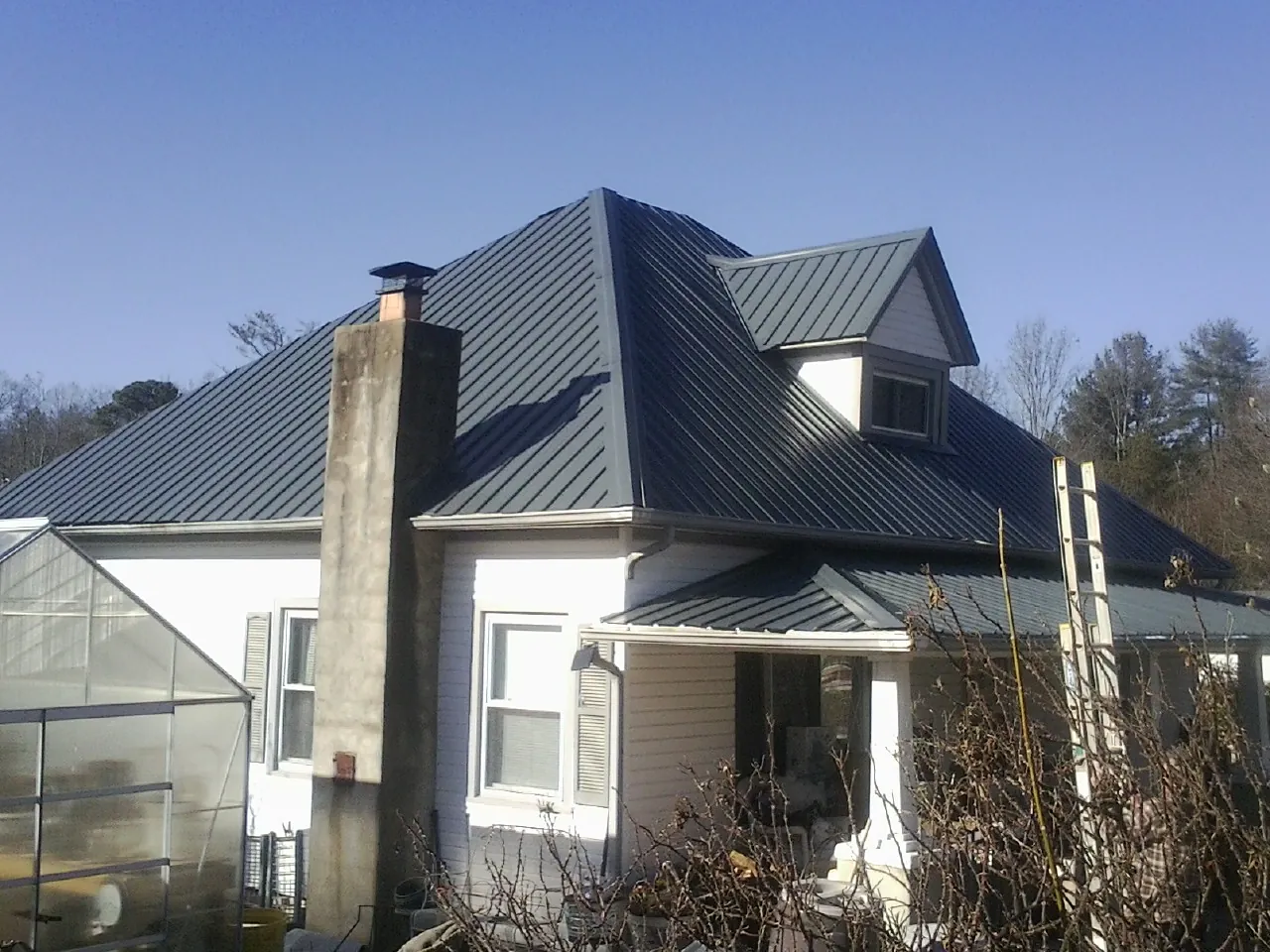 Dark blue standing seam metal roof on a white farmhouse with dormer — Slate & Tile Roof Repair by Roofing Brothers in Epworth