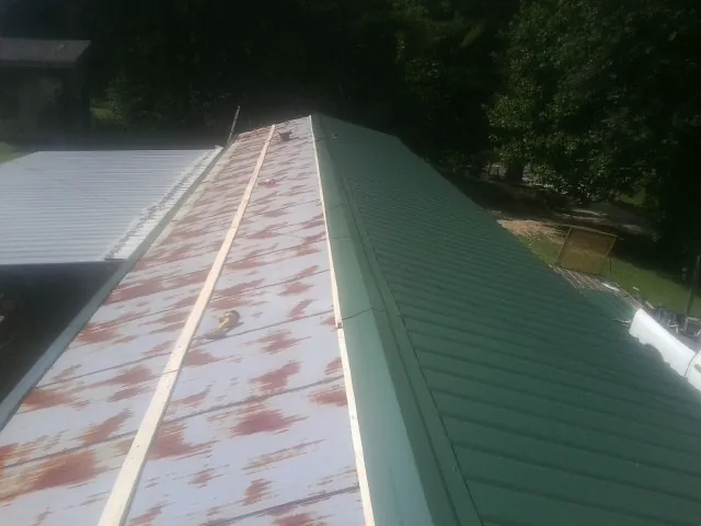 Old rusted panels beside newly installed green metal roofing — Wind Damage Roof Repair by Roofing Brothers in Epworth