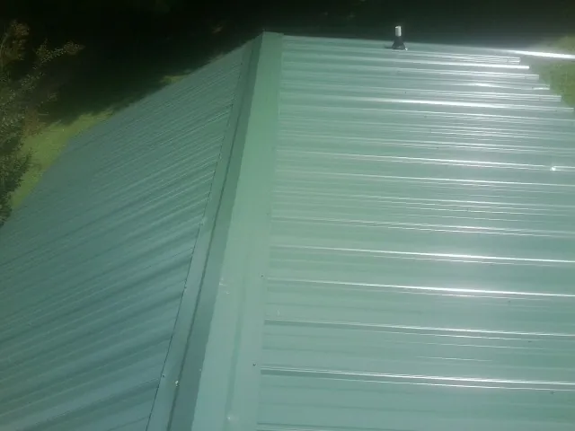 New green metal panels meeting at the ridge of a roof — Flat Roof Repair work by our crew in Epworth