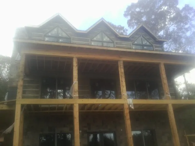 Dormers and porch framing on a large log home under construction — Roof Coating work by our crew in Epworth